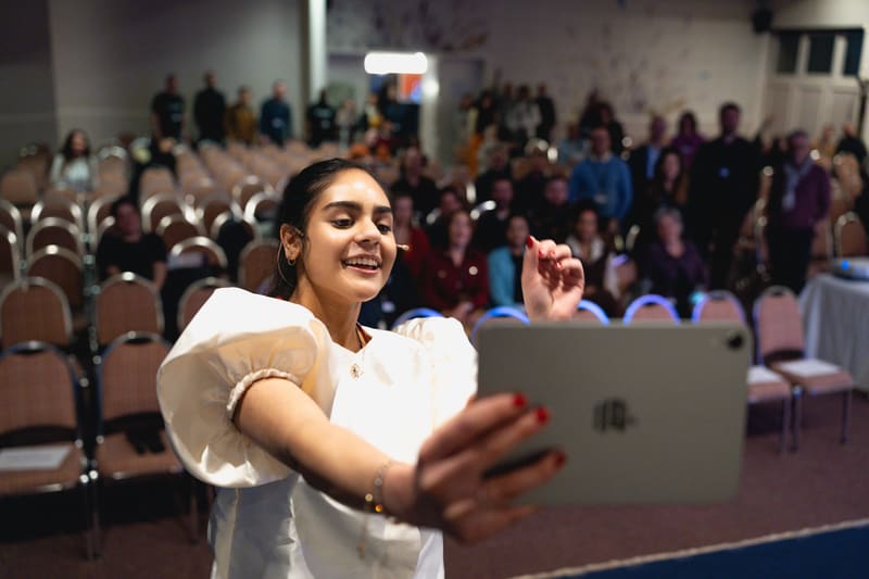 Master of Ceremonies Avanti Sharma taking a selfie with the LSTE 2025 audience